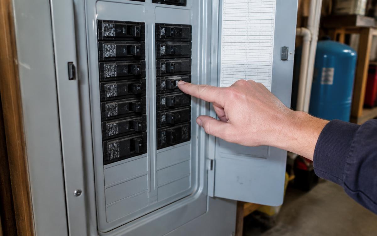 Technician pointing at a tripped breaker in a home electrical panel
